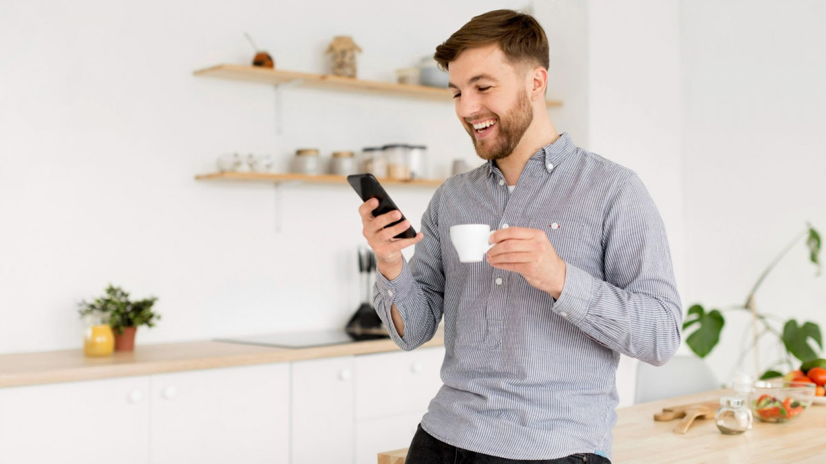 Portrait man drinking coffee while checking mobile